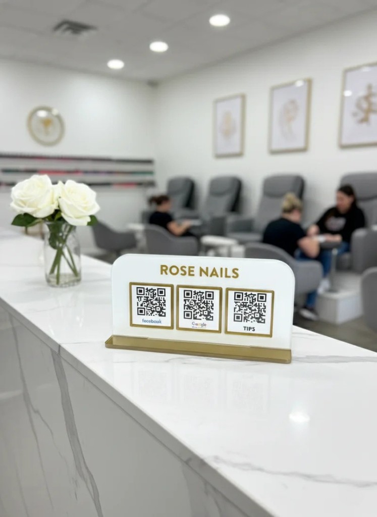 TapMeGo stand with gold QR frames on a marble reception counter
